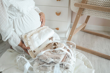Pregnant woman is getting ready for the maternity hospital, packing baby stuff. pregnant woman preparing and planning baby clothes