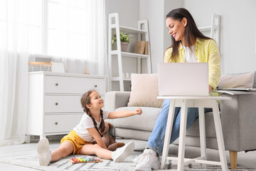 Little girl playing with xylophone while her mother working at home