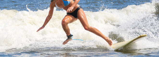 Teenage girl wearing a bikini falling off of her surfbord into the water while surfing