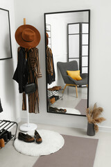 Interior of light hallway with mirror, rack and shoe stand