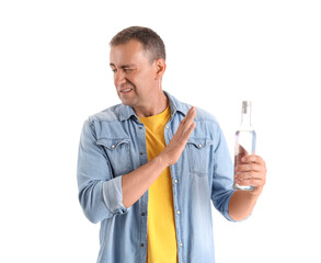 Displeased mature man rejecting bottle of vodka on white background
