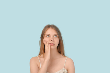 Young woman suffering from toothache on blue background