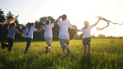 children run through the meadow in the park with toys in their hands. happy family kid dream...