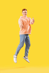 Fototapeta na wymiar Jumping young man with tasty hot dogs on yellow background