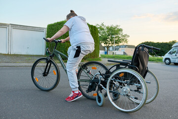 Boy transfers from wheelchair to bike, activity rehabilitation health concept