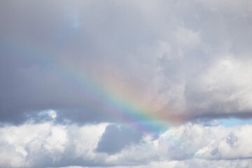 Fototapeta na wymiar Natural rainbow in the cloudy sky
