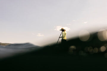 A young woman cools off in an alpine lake at the base of Mt. Hood with her standup paddle board on a summer day.