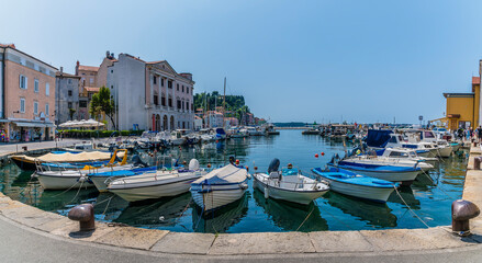 Fototapeta na wymiar A view across boats moored in the inner harbour towards the town of Piran, Slovenia in summertime