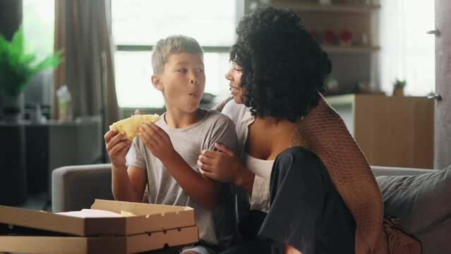 Portrait of adorable little boy child kid and his young mother mom eating pizza with great pleasure and enjoying beautiful day together at home Happy childhood and cute family concept