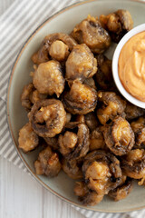 Homemade Crispy Deep Fried Mushrooms with Spicy Mayo on a Plate on a white wooden background, top view. Close-up.