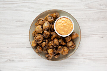 Homemade Crispy Deep Fried Mushrooms with Spicy Mayo on a Plate on a white wooden background, top view.