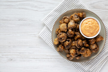 Homemade Crispy Deep Fried Mushrooms with Spicy Mayo on a Plate on a white wooden background, top view.