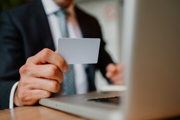 Man holding a credit card in his hand while using it for an online payment.