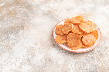 Slices of dehydrated salted meat chips on gray concrete, side view, copy space