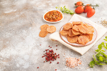 Slices of dehydrated salted meat chips on gray concrete, side view, copy space