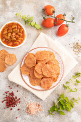 Slices of dehydrated salted meat chips on gray concrete, top view