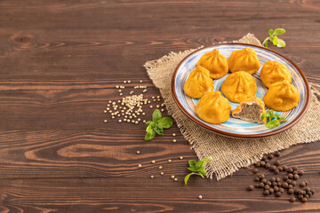Manti dumplings with pepper, basil on brown wooden. Side view, copy space.