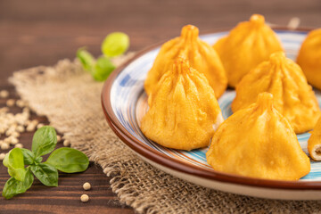Manti dumplings with pepper, basil on brown wooden. Side view, selective focus