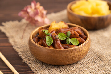 Tteokbokki or Topokki, fried rice cake stick, on brown wooden, side view, selective focus