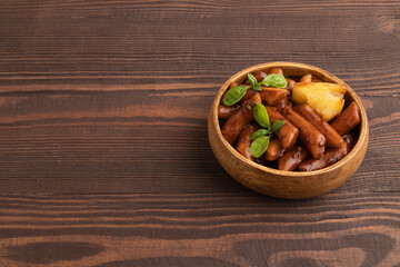 Tteokbokki or Topokki, fried rice cake stick, on brown wooden, side view, copy space