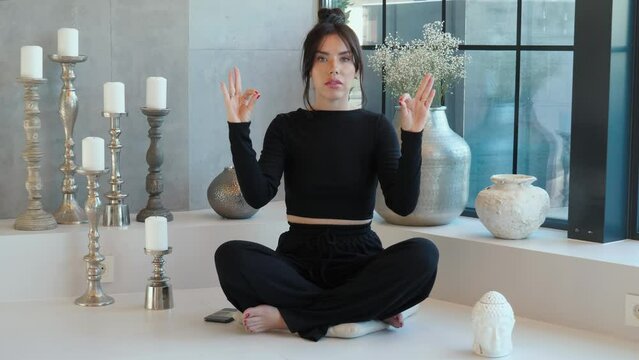 Woman is talking, sits cross-legged, participating yoga in video conference, remotely negotiating with clients, showing on her fingers. Video tutorial for work or study