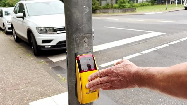 male hand presses button to turn on traffic light at pedestrian crossing, participation in traffic management through activation of buttons, promoting collaborative approach urban mobility