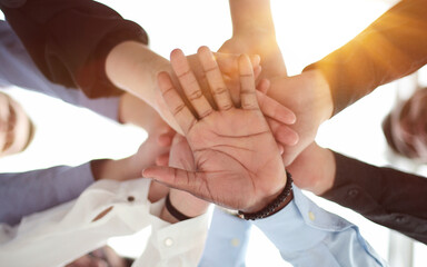 Close up bottom view of people putting their hands together.