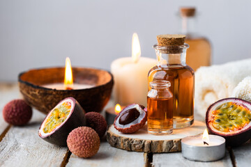 Glass bottles with pure organic essential litchi and passion fruit oil on wooden background. Concept of natural ingredients for beauty treatment, skin care, massage. Exotic fruits extract and essence