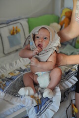 mãe colocando roupa em bebê em casa 