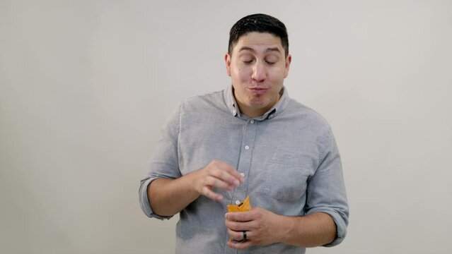 Extremely happy hispanic man eating dry snack, closing eyes with pleasure. Middle-aged man chewing snack thoroughly, enjoying the taste, nodding head. High quality 4k footage
