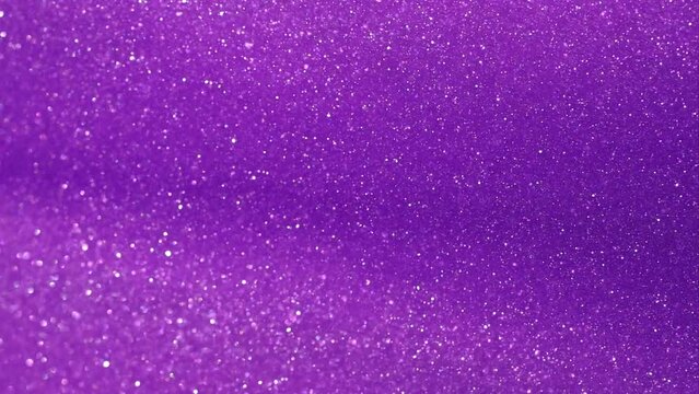 Abstract particle motion background. Silvery dust particles sparkling and floating in purple liquid. Shiny glitters in fluid. Slow Motion 4K footage.
