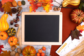 October is an inscription on the calendar and a frame lying on colored autumn leaves. Hello autumn, back to school, harvesting concept, flat lay. Space for text.