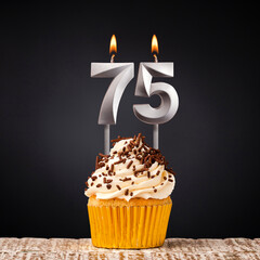 birthday cupcake with number 75 candle - Celebration on dark background