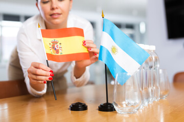 Little flag of Argentina on table with bottles of water and flag of Spain put next to it by...