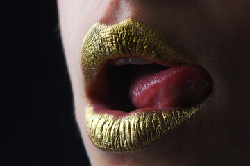 Sexy tongue licking lips. Sensual woman mouth. Sexy girl golden lips, gold mouth. Glowing gold skin and gild lips. Metallic shine golden lip gloss.