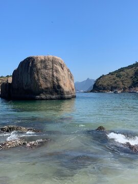 Close da Pedra da Baleia com o Corcovado ao fundo e &aacute;guas cor esmeralda na prainha de piratininga em Niter&oacute;i no Rio de Janeiro.