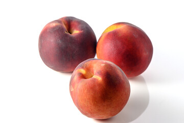 three fresh appetizing peaches on a white background, studio shooting