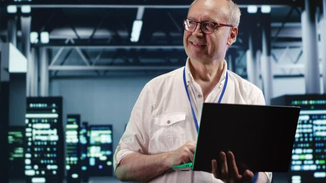 Seasoned computer scientist expertly managing data while navigating in industrial server room. Efficient IT consultant ensuring optimal cybersecurity protection, optimizing systems