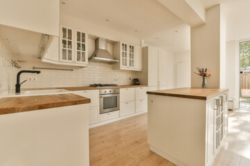 a kitchen with all white cabinets and wood counter tops on the island in front of the door to the patio