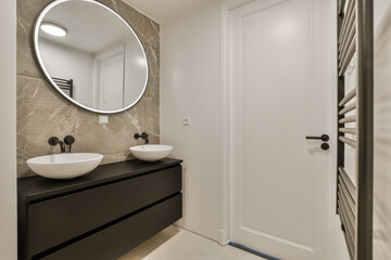 a bathroom with two sinks and a large round mirror on the wall in front of the sink is dark wood