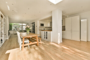 Fototapeta premium a kitchen and dining area in a house with wood floors, white cabinets and an open floor to the living room
