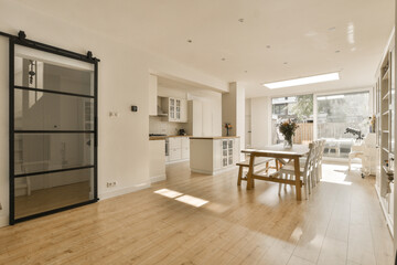 a kitchen and dining area in a house with wood floors, white walls and doors open to the living room