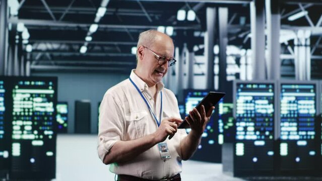 Precise IT professional navigating network of server rows in industrial hub. Computer operator with laptop ensuring proper operations, doing optimizations and maintenance in data center