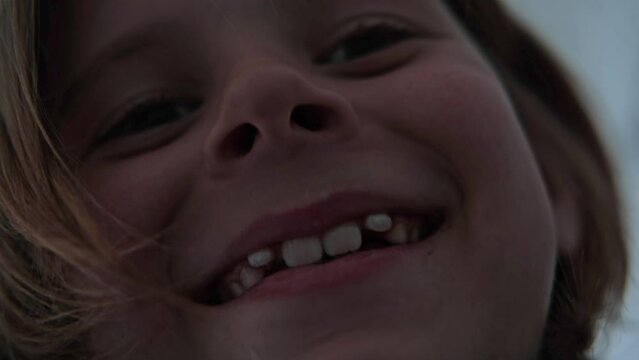 A young boy is filming himself. Full screen face, close-up. Boy 9 years old. He smiles. He has crooked teeth.