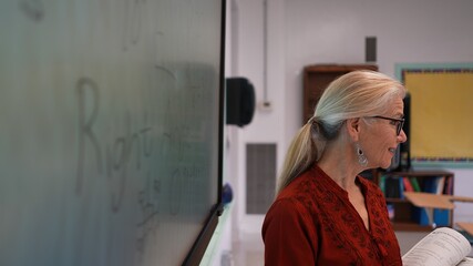 Closeup of happy female teacher writing on an interactive whiteboard teaching geometry math in a school classroom.