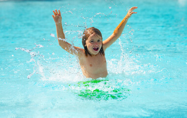 Child splashing in summer water pool. Kid splash in pool. Excited happy kid boy jumping in pool, water fun. Kid jumping in the swimming pool and splashing water. Kid splashing on poolside.