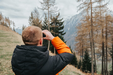 Man with binoculars..Hiking in the mountains in the spring season.man in a warm jacket looks through binoculars at a mountain landscape. walking in the mountains