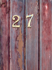 Number 27 on red painted old wooden wall.