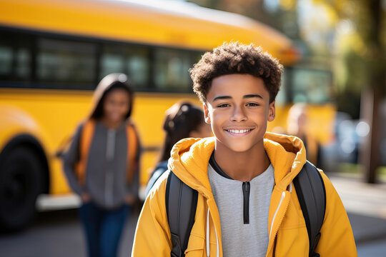 A young boy standing in front of a cheerful yellow school bus