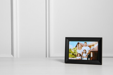 Framed family photo on white wooden table indoors, space for text